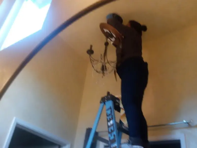 Electrician installing a chandelier in a Seymour residence